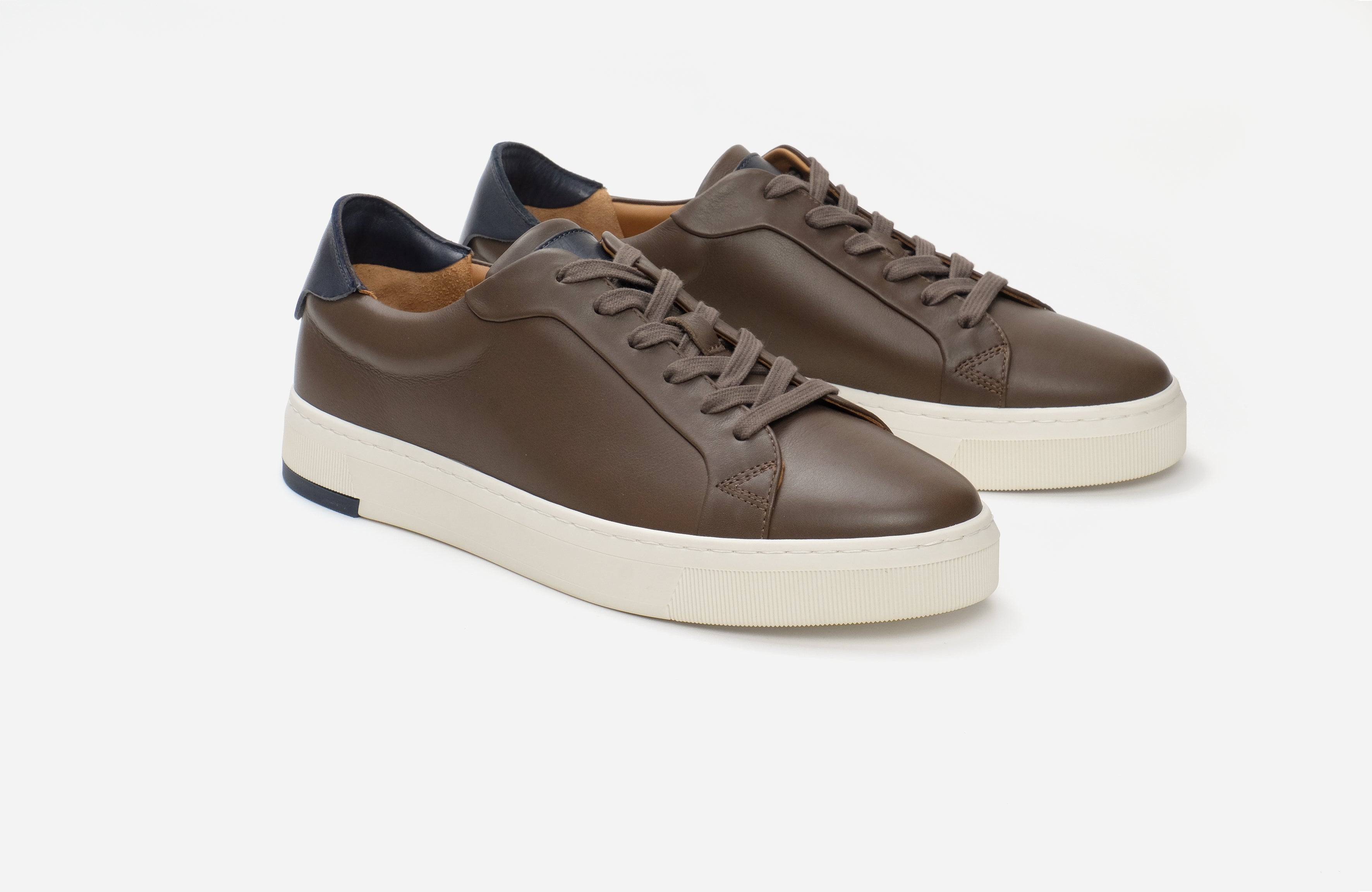 Brown leather sneakers with white soles on a light gray background