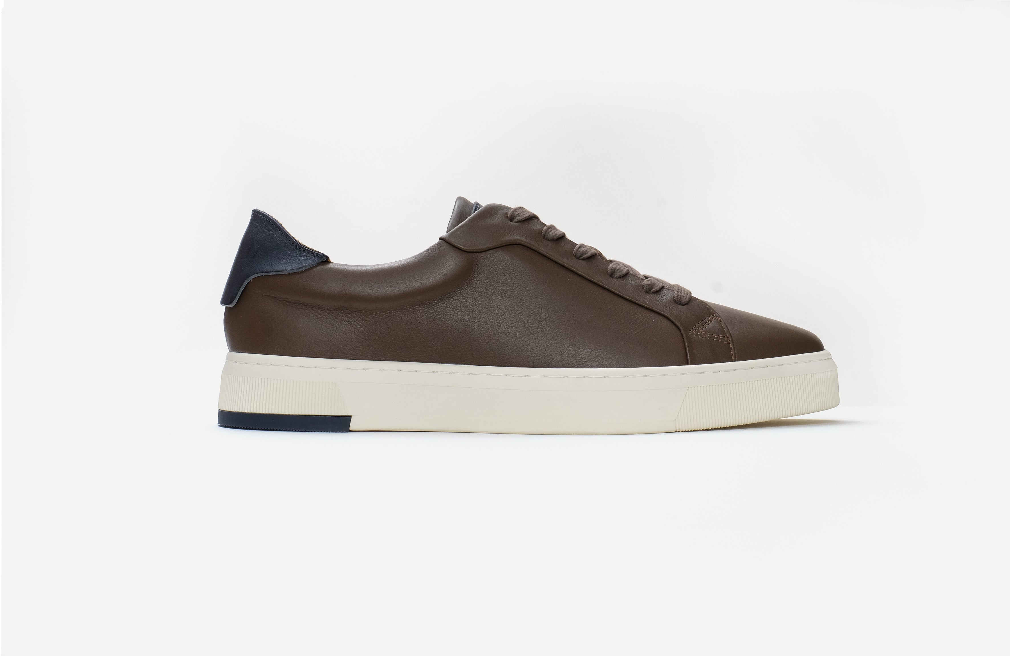 Brown sneaker with a white sole on a light gray background