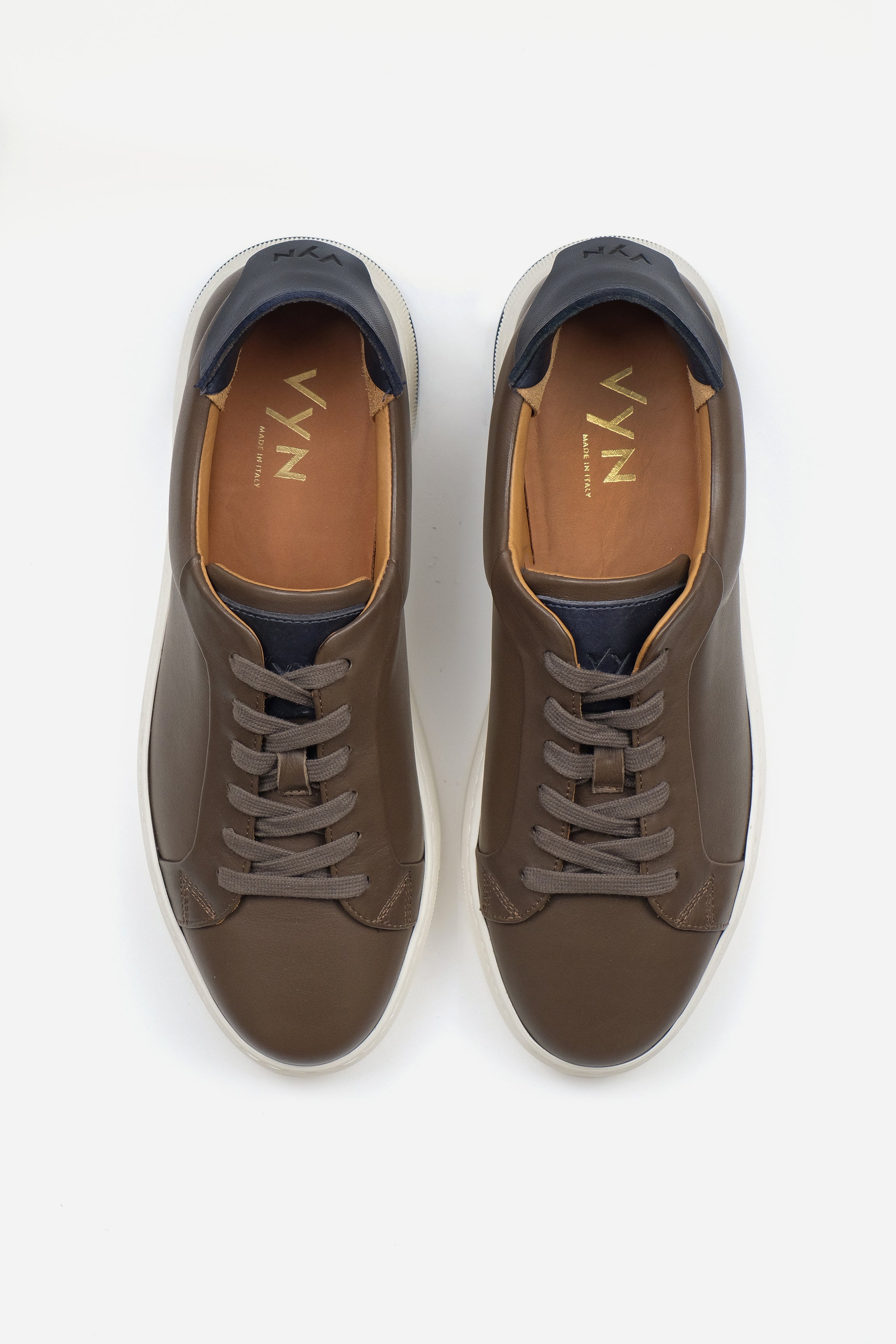 Pair of brown sneakers with navy accents on a white background